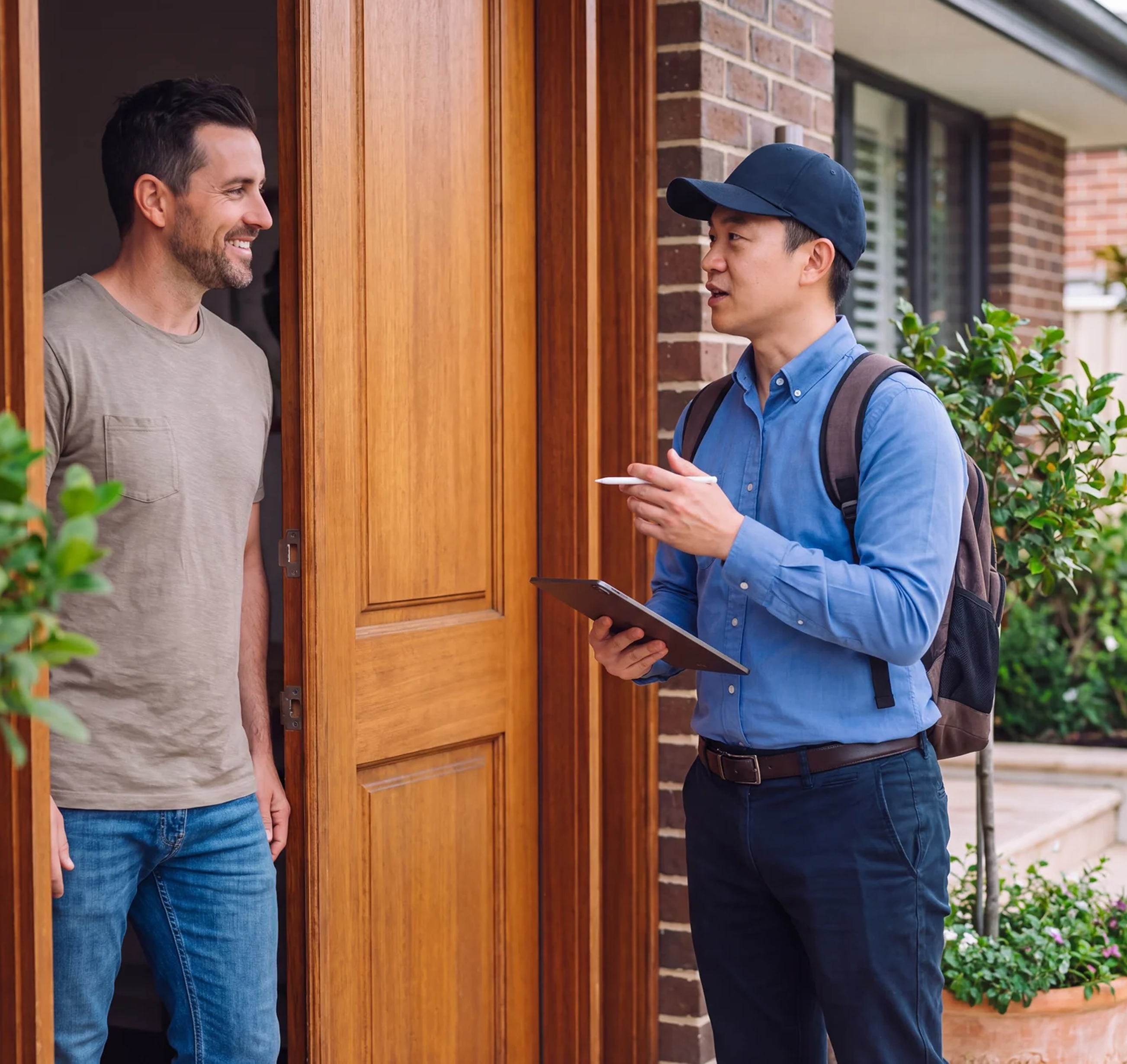 A home services technician talking with a homeowner at the front door